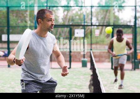 Junger erwachsener Mann, der im Freien Paddeltennis spielt Stockfoto