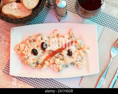 Olivier-Salat aus gekochtem Gemüse, garniert mit schwarzen Oliven Stockfoto