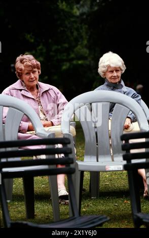 Zwei ältere Frauen sehen sich Blasmusik an, die in einem Parkbandstand Musik spielt Stockfoto