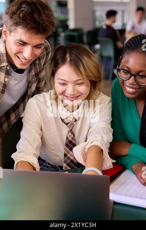 Gruppe von verschiedenen multiethnischen, lächelnden jungen Studenten, die mit einem Laptop lernen und sich im Klassenzimmer treffen Stockfoto