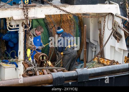 18. April 2024. Fraserburgh Harbour, Aberdeenshire, Schottland. Hier sind 2 Fischer an Bord eines Fischerbootes, die im Hafen von Fraserburgh anlegen und die F reparieren Stockfoto