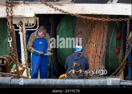 18. April 2024. Fraserburgh Harbour, Aberdeenshire, Schottland. Hier sind 2 Fischer an Bord eines Fischerbootes, die im Hafen von Fraserburgh anlegen und die F reparieren Stockfoto