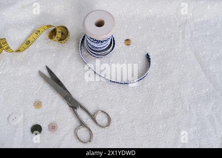 Weiße Leinenserviette, mit handgemachter Spitze beschnitten, in mehreren Schichten gerollt, zarte Schneeglöckchenblume, Schere, Knöpfe, Band ist auf Lichttisch, Conce Stockfoto