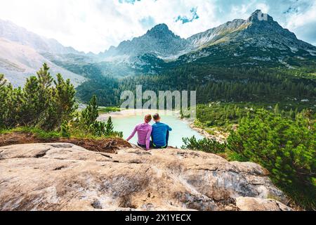 Beschreibung: Junges sportliches Paar genießt am Nachmittag von einem schönen Rastplatz aus den Blick auf den türkisfarbenen Sorapis-See. Sorapissee, Dolomiten, Bel Stockfoto