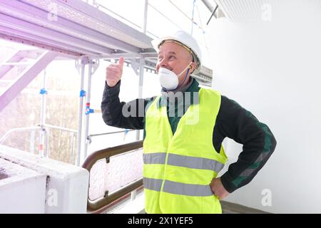 Leitender männlicher Baumeister, Arbeiter im weißen Schutzhelm, in Arbeitskleidung steht auf einer Baustelle, das Konzept der Reparatur von Gebäuden, Strukturen, s Stockfoto