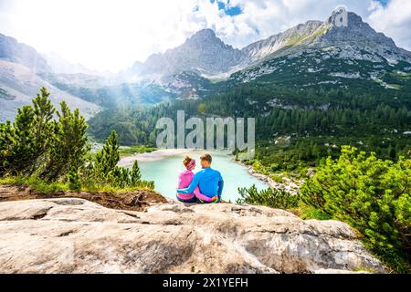 Beschreibung: Junges sportliches Paar genießt am Nachmittag von einem schönen Rastplatz aus den Blick auf den türkisfarbenen Sorapis-See. Sorapissee, Dolomiten, Bel Stockfoto