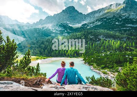 Beschreibung: Junges sportliches Paar genießt am Nachmittag von einem schönen Rastplatz aus den Blick auf den türkisfarbenen Sorapis-See. Sorapissee, Dolomiten, Bel Stockfoto