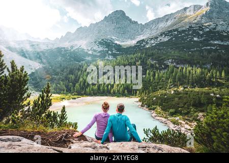 Beschreibung: Junges sportliches Paar genießt am Nachmittag von einem schönen Rastplatz aus den Blick auf den türkisfarbenen Sorapis-See. Sorapissee, Dolomiten, Bel Stockfoto