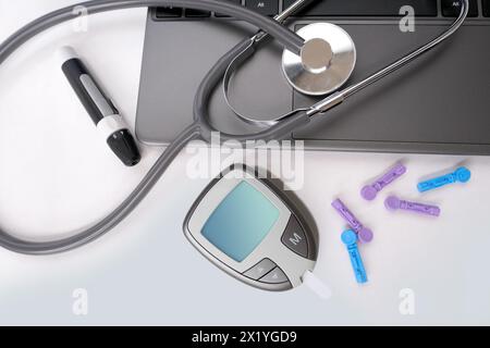 Medizinisches Stethoskop, Diabeteslanzette mit Ersatznadeln, Glucometer, Laptop-Tastatur auf weißem Hintergrund, Ausrüstung für Blutzuckermessung an h Stockfoto