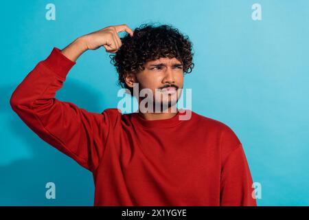 Porträt des nachdenklichen jungen Mannes Hand Finger Kratzkopf Blick interessiert leeren Raum isoliert auf blauem Hintergrund Stockfoto