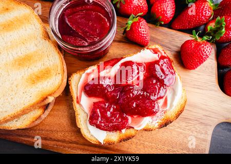 Toastscheibe mit hausgemachten Erdbeerkonserven und Cream Cheese: In Scheiben geröstetes Weißbrot und hausgemachte Erdbeerkonserven und Neufchatel Stockfoto