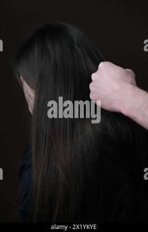 Die Faust eines Mannes vor einer weinenden Frau, Nahaufnahme auf dunklem Hintergrund, Vorstellung von Stress, psychologischer Gewalt, häuslichem Missbrauch Stockfoto