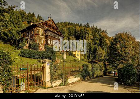 Herbststimmung mit Alpenhaus und Wanderpaar im Hintergrund auf der Mondseestraße in St. Gilgen, Wolfgangsee, Salzburger Land, Alpen, Österreich Stockfoto