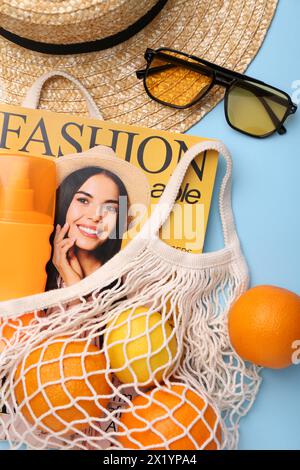 Schnur-Tasche mit Magazin, Obst und Sommeraccessoires auf hellblauem Hintergrund, flach gelegt Stockfoto