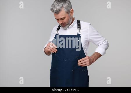 Mann mit Küchenschürze auf grauem Hintergrund. Modell für Design Stockfoto