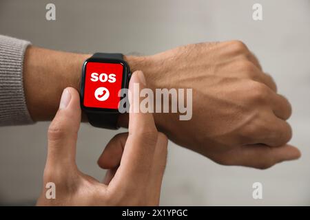 Mann mit SOS-Funktion bei Smartwatch drinnen, Nahaufnahme Stockfoto