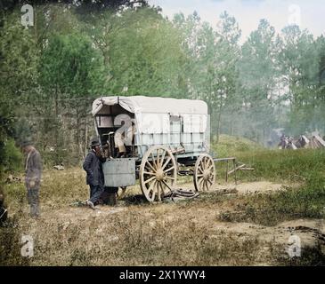 Feldfernschreiber, Batteriewagen. Jahr: September 1864. Standort: Petersburg, Virginia. Von: David Knox. Ansicht eines Wagens, der eine große Batterie hält, die den Feldtelegraphen antreibt, auf einer Rodung in der Nähe eines Lagers der Union Army. Ein Mann steht an einem Ende des Wagens und legt einen Ellbogen auf den Wagen, während er eine Pfeife raucht. Ein zweiter Mann sitzt im Wagen und schreibt in einem Notizbuch, das offen auf einem Tisch vor ihm liegt. Der Wagen hat ein gemaltes Schild mit der Aufschrift „Military Telegraph H'Q'rs Battery Wagon“, das die Seite des Wagens bedeckt und Zelte und Soldaten sind im Hintergrund zu sehen. Stockfoto