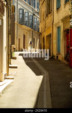 Frau, die an einem heißen Tag in Arles, Frankreich, die Straße runter läuft. Stockfoto
