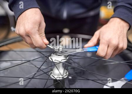 Nicht erkennbare Person, die eine Radachse nach der Demontage zur Reinigung und Schmierung im Rahmen einer Fahrradwartung montiert hat. Echt Peo Stockfoto