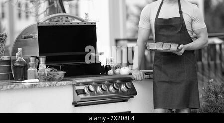 Mann mit Grilllachs. Mann kocht Lachs auf dem Grill. Küchenchef kocht Lachs auf Grill im Freien. grill Lachsfisch bei man trägt Schürze. Stockfoto