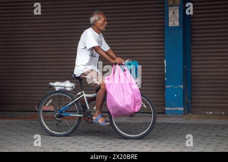 SAMUT PRAKAN, THAILAND, 16. März 2024, ein älterer Radfahrer mit großer Tasche fährt auf dem Bürgersteig entlang Stockfoto