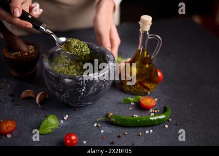 Frau, die grüne Soße in einem Steinmörtel mischt Stockfoto