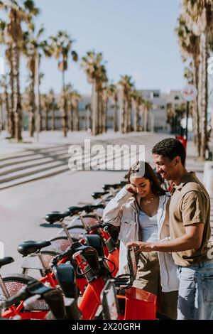 Junge Paare, die einen luftigen Tag mit Fahrrädern von einer Verleihstation in Barcelona verbringen. Stockfoto