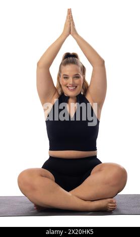Kaukasische junge Frau plus Größe Modell auf weißem Hintergrund, Yoga üben, auf Matte sitzen Stockfoto