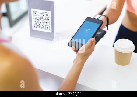 Birassische und kaukasische Frauen im Pilates-Studio scannt man QR-Code mit Smartphone Stockfoto