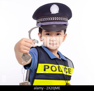 Ein Kind, das als Polizist gekleidet ist und Handschellen zeigt Stockfoto