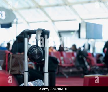 Nahaufnahme von Audio-Kopfhörern, die in einem Trolley im internationalen Flughafen Paris hängen und am Flugsteig auf das Einsteigen in das Flugzeug warten. Hintergrund zeigt verschwommene e s an Stockfoto