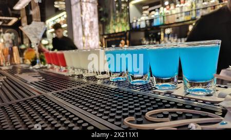 Blue Lagoon, White Cosmopolitan und Pink Lady Cocktail Shots werden in Serie für eine Gruppe von Freunden platziert, die sie im heißen Sommer an der Bar genießen können. Club A Stockfoto