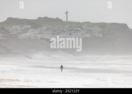 Promeneur solitaire se promenant sur la plage de Le Portel lors de la tempête Pierrick, Frankreich, Côte d'opale. Stockfoto