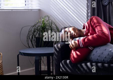 Afroamerikanische junge Frau, die zuhause auf einer Couch ruht, nachdenklich aussieht, Kopierraum Stockfoto