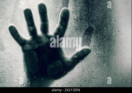 Bemannt Figur mit Händen gegen mattiertes Glas gedrückt. Schatten eines Mannes hinter dem matten Glas verschwommene Hand und Körper weichen Fokus. Freiheitskonzept Stockfoto