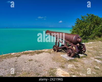 Antigua - 26. Januar 2024: Eine Kanone bei Fort James auf der Insel Antigua in der Karibik. Die Kanone stammt aus dem Jahr 1805. Ein blauer Himmel und türkisfarbenes Wasserkleid Stockfoto