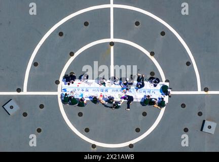 TAIZHOU, CHINA - 19. APRIL 2024 - Schüler der Mittelstufe ziehen die lange Rolle eines Kriegsschiffes im Naval Ship Cultural Park in Taizhou, Provinz Jiangsu. Stockfoto