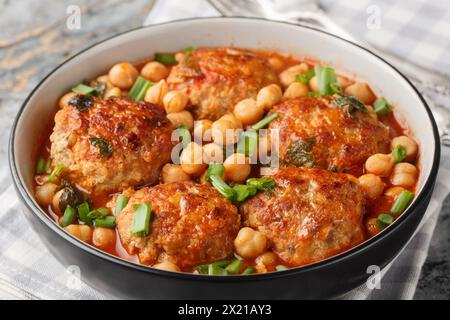 Scharfe frittierte Fleischbällchen mit Kichererbsen, Tomaten, Minze und grünen Zwiebeln in einer Schüssel auf dem Tisch. Horizontal Stockfoto