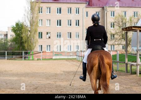 Reiter zu Pferd mit Blick auf die Stadt. Weiblicher Jockey im Uniform-Reitpferd. Pferdesport Stockfoto