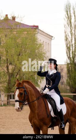 Reiter, der auf dem Pferderücken in der städtischen Reitarena grüßt. Dressur. Weiblicher Jockey in Uniform. Pferdesport. Reitschule Stockfoto