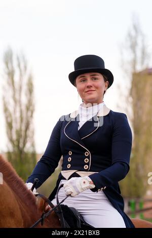 Reitsport in Dressurkleidung auf Kastanienpferd. Porträt weiblicher Jockey. Reitschule Stockfoto