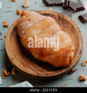 Nahaufnahme eines xuixo de Crema, ein Gebäck gefüllt mit Pudding typisch für katalonien, spanien, auf einem Holzteller, auf einer rustikalen grauen Oberfläche Stockfoto