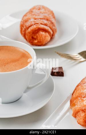 Eine Tasse Kaffee und ein paar Xuixos de Crema, Gebäck gefüllt mit Pudding typisch für katalonien, spanien, auf einem gedeckten Tisch Stockfoto