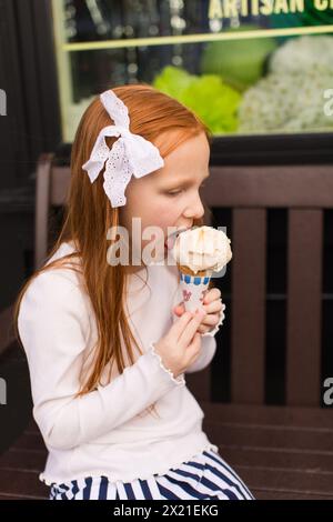 Rothaariges Mädchen isst Eisbecher Stockfoto