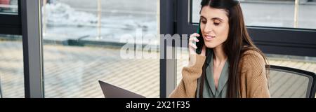 Eine Frau, die an einem Tisch in einer Geschäftsumgebung saß, hatte ein Gespräch auf einem Handy. Stockfoto