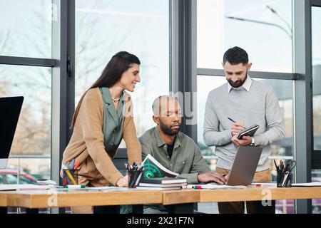 Eine vielfältige Gruppe von Fachleuten versammelt sich mit einem Laptop an einem Tisch, um an einem Projekt in einer modernen Büroumgebung, Vielfalt und Integration zusammenzuarbeiten Stockfoto