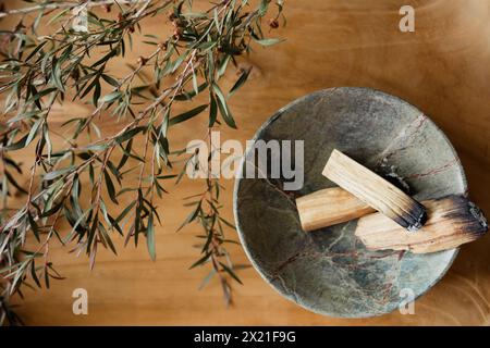 Palo Santo steckt in einer Marmorschale mit manuka auf hölzernem Hintergrund Stockfoto