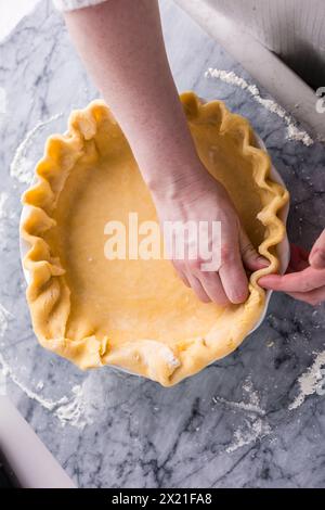 Eine geriffelte Kuchenkruste auf einer Marmorplatte vorbereiten Stockfoto