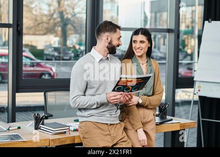 Ein Mann und eine Frau in Geschäftskleidung stehen Schulter an Schulter und symbolisieren Teamarbeit und Zusammenarbeit in einer modernen Büroumgebung. Stockfoto