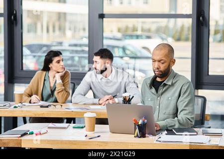 Drei Personen nehmen an einem produktiven Meeting Teil, um einen Laptop herum, um ein Projekt in einem modernen Büroumfeld zu diskutieren. Stockfoto